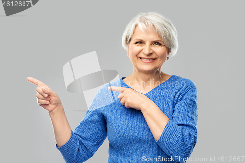 Image of smiling senior woman pointing fingers to something