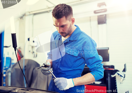 Image of mechanic man with wrench repairing car at workshop