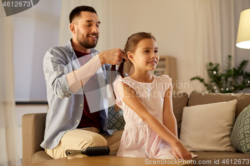 Image of father braiding daughter hair at home