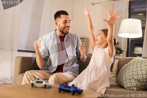 Image of father and daughter playing video game at home