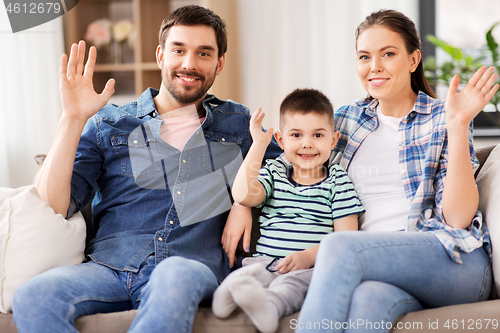 Image of portrait of happy family waving hands at home