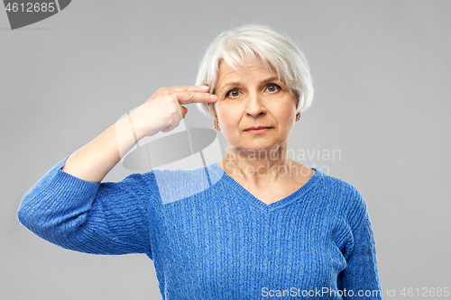 Image of senior woman making making finger gun gesture