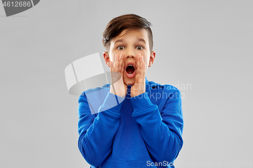 Image of scared boy in blue hoodie shouting or calling