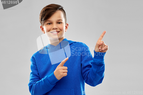 Image of happy boy in blue hoodie pointing fingers upwards