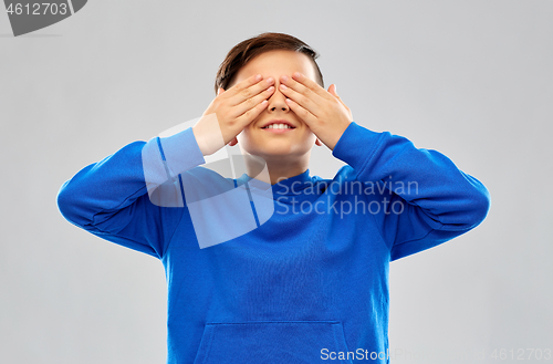 Image of boy in blue hoodie closing his eyes by hands