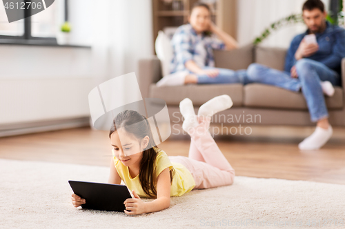 Image of girl with tablet computer lying on floor at home