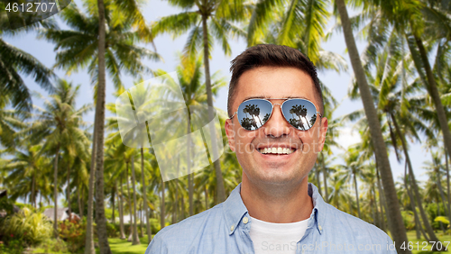 Image of smiling man in sunglasses over tropical beach