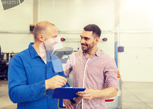 Image of auto mechanic with clipboard and man at car shop