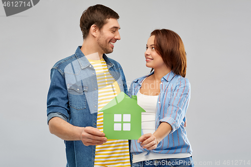 Image of smiling couple holding green paper house