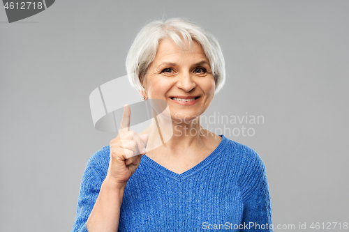 Image of smiling senior woman pointing finger up