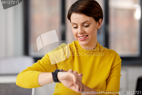 Image of happy businesswoman using smart watch at office