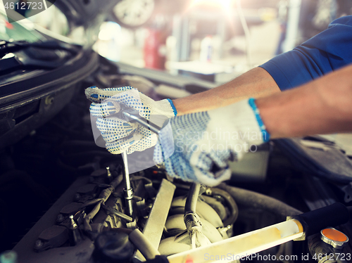 Image of mechanic man with wrench repairing car at workshop