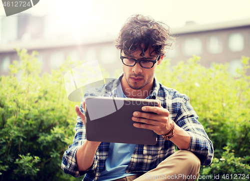 Image of man in glasses with tablet pc on city steet