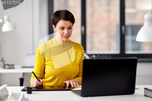 Image of designer with laptop and pen tablet at office