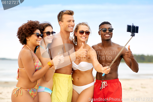 Image of friends taking selfie on beach and show thumbs up