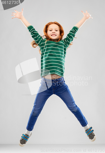 Image of smiling red haired girl in striped shirt jumping