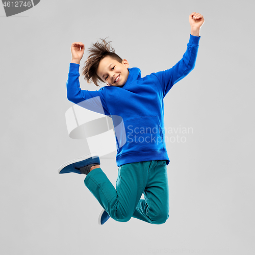Image of portrait of smiling boy in blue hoodie jumping