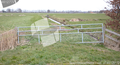 Image of Metal fence and farm gate leading into grassy field