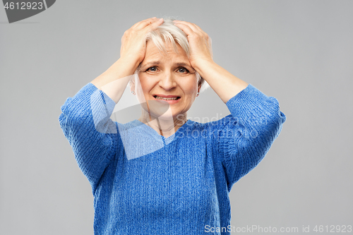 Image of stressed senior woman holding to her head