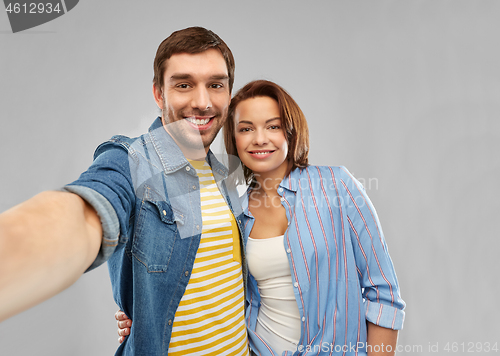 Image of happy couple taking selfie over grey background