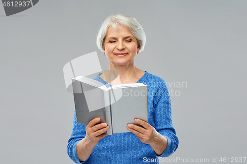 Image of senior woman reading book over grey background