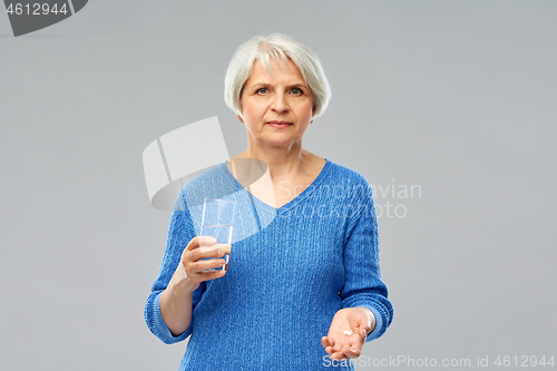 Image of senior woman with glass of water and pills