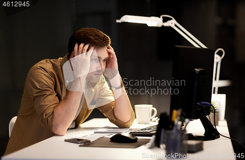 Image of man with computer working late at night office