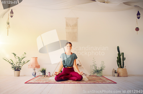 Image of woman meditating in lotus pose at yoga studio