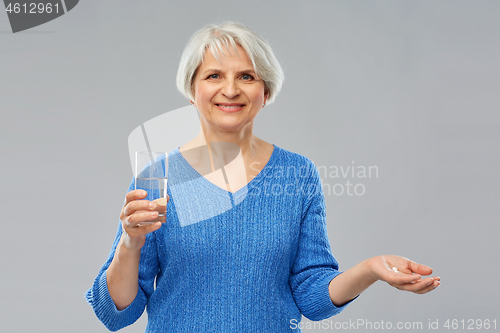 Image of senior woman with glass of water and pills