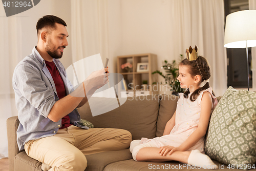 Image of father photographing daughter by cellphone at home