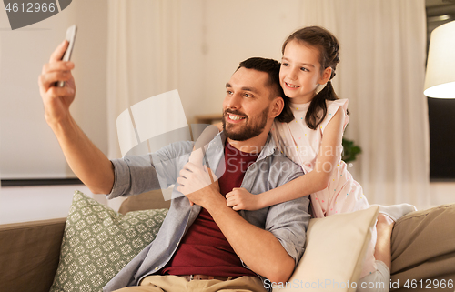 Image of father and daughter taking selfie at home