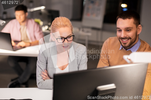 Image of business team with computer working late at office