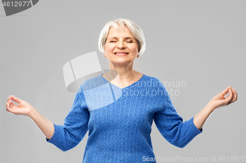 Image of smiling senior woman in blue sweater chilling