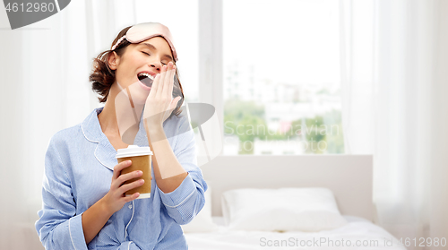 Image of woman in pajama and eye mask with coffee yawning