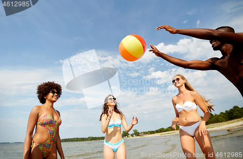 Image of happy friends playing ball on summer beach