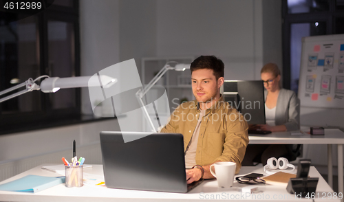 Image of man with computer working late at night office