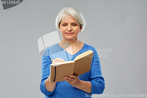 Image of senior woman writing to diary or notebook