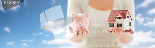 Image of close up of woman with house model and piggy bank