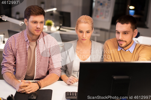 Image of business team with computer working late at office