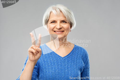 Image of portrait of smiling senior woman showing peace