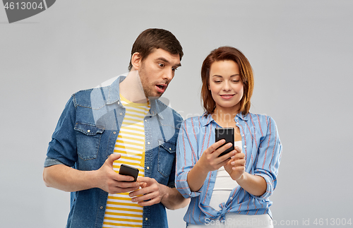 Image of couple using smartphones over grey background