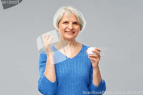 Image of smiling senior woman with jar of face cream