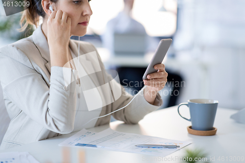 Image of businesswoman with earphones and smartphone