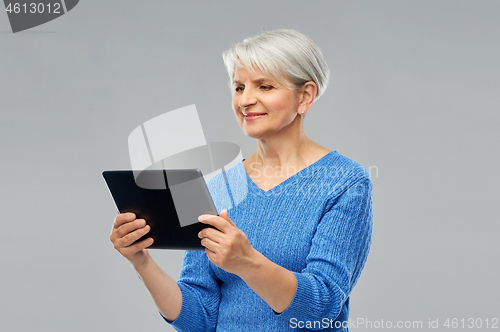 Image of senior woman in glasses using tablet computer