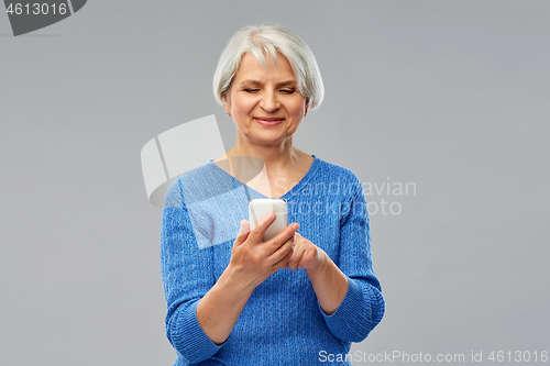 Image of smiling senior woman using smartphone