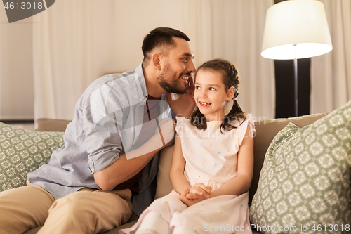 Image of happy father whispering secret to daughter at home