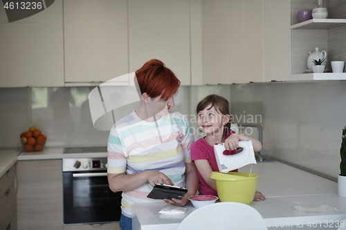 Image of Mother and daughter playing and preparing dough in the kitchen.