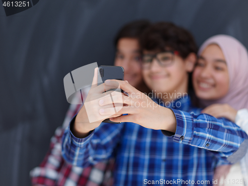 Image of group of arab teens taking selfie photo on smart phone