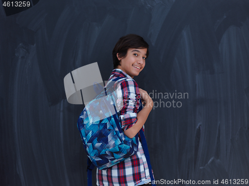 Image of arab teenager  with schoold backpack against black chalkboard