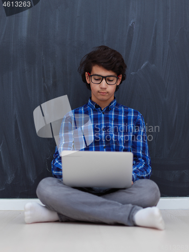 Image of Arab teenager using laptop to work on homework  at home